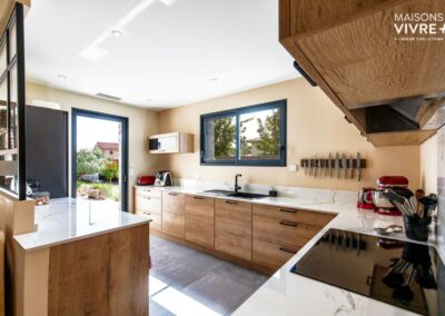 Espace cuisine lumineux avec meubles facade bois et plans de travail en marbre - Maison moderne avec piscine près de Villefranche sur Saône